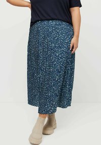 Plisserad midi kjol i mörkblått med blommönster i ljusblått och grönt. Matchas med beiga ankelskor med mönstrad sula.