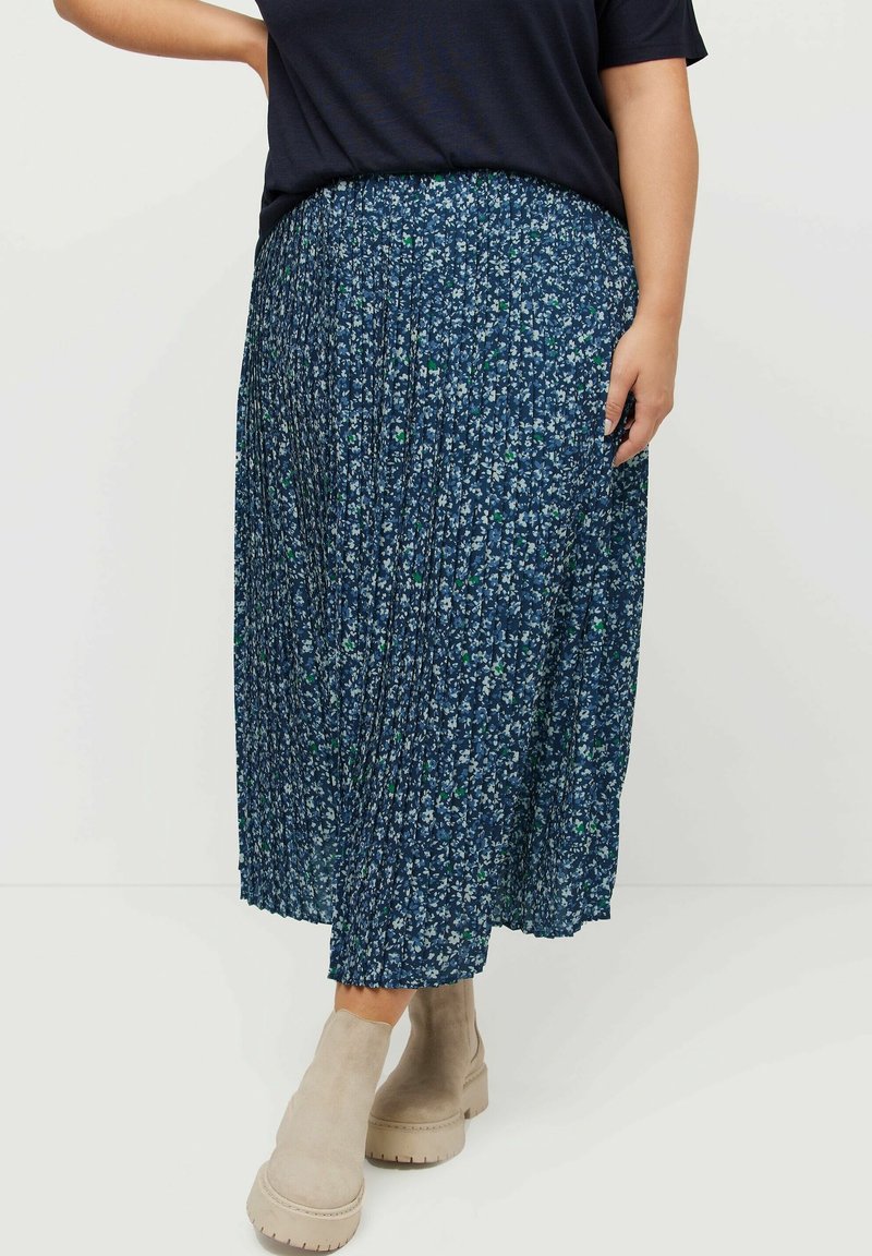 Plisserad midi kjol i mörkblått med blommönster i ljusblått och grönt. Matchas med beiga ankelskor med mönstrad sula.