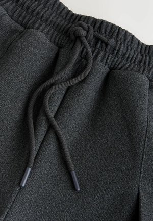 Tumedat hallid dressipüksid, millel on elastne vöökoht paelaga, pehme tekstuur ja kaks küljetaskut.