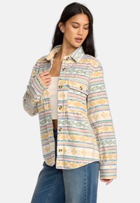 Flanellhemd mit einem pastellfarbenen Muster aus Wellen und geometrischen Formen. Knopfverschluss vorne, zwei Brusttaschen und ein umgeschlagener Kragen.