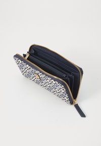 Navy and white patterned zip wallet with gold hardware. Features multiple card slots and an inner zip pocket. Made of textile and leather.