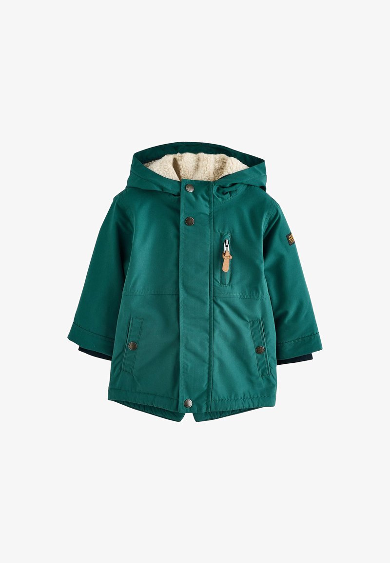 Giacca verde, isolata, con cappuccio, foderata in pelliccia sintetica, chiusure a bottoni e cerniera, e ampie tasche laterali. Presenta un tessuto texturizzato e polsini contrastanti in navy.