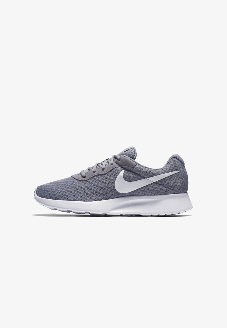Chaussure de running Nike grise avec logo Swoosh blanc, tige en mesh, design à lacets et semelle blanche épaisse sur fond blanc.