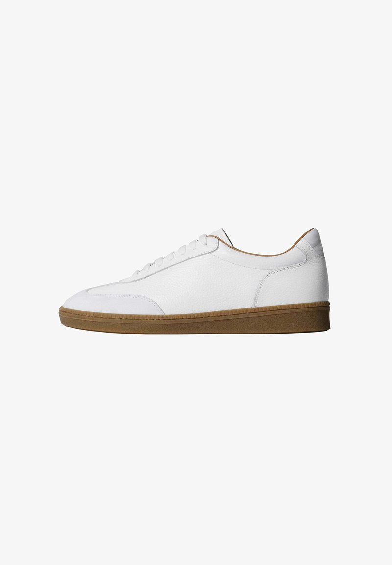 Zapatilla blanca baja con diseño de cordones y suela de goma marrón texturizada, mostrada en perfil derecho sobre fondo blanco.