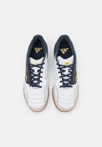 Scarpe sportive bianche con accenti blu navy e branding dorato, caratterizzate da una tomaia in pelle testurizzata, chiusura con lacci e suola in gomma.
