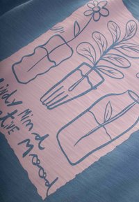Blauer Stoff mit einer rosa Illustration, die drei Glasvasen, florale Designs und den Text "Achtsamer Minimalismus" zeigt. Glatte Textur.
