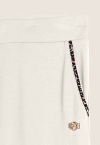 Pantalones de chándal gris claro con una textura suave, que cuentan con un ribete de bolsillo de estampado de leopardo y un acento de logotipo metálico en la parte delantera.