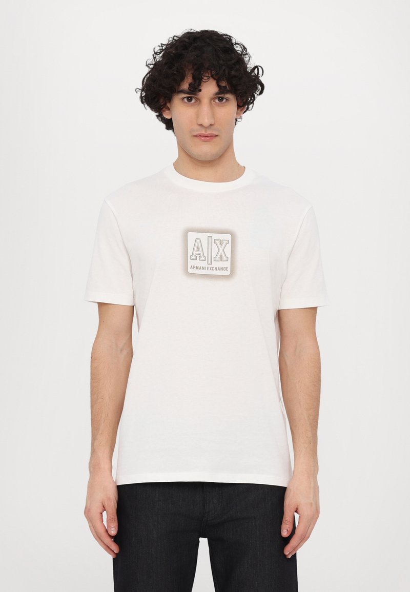 White cotton t-shirt with short sleeves and a round neckline. Features a prominent gray logo on the chest, with a simple design.