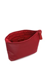 Crvena torbica sa patentnim zatvaračem napravljena od glatkog materijala, sa teksturiranim zatvaračem i unutrašnjim džepom, minimalističkog dizajna i zaobljenog oblika.