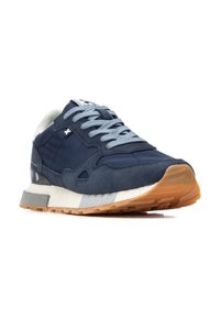 Zapatilla en color navy con una mezcla de texturas lisas y de ante, cordones gris claro, un acento blanco y una suela de goma con diseño moteado.