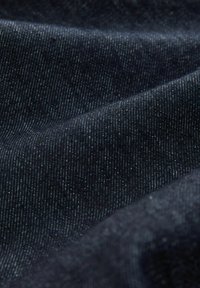 Donkerdenim stof met een lichte glans, voorzien van verticale strepen, een zachte textuur en een gladde, golvende plooi.