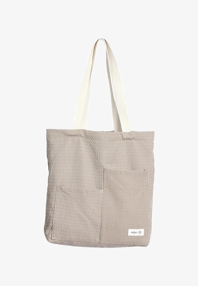 Bézs csíkos vászontáska két bézs színű szövetpánttal. Két első zsebbel és az alsó jobb sarokban címkével rendelkezik. Organikus pamutból készült.