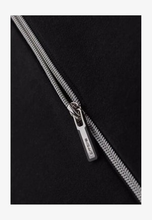 Schwarzer Stoff mit einem silbernen Reißverschluss und einem markierten Zugband, das die glatte Textur und die präzise Naht entlang der Kante betont.