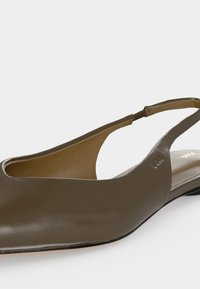 Chaussure plate slingback en cuir vert olive avec bout pointu et petit talon, équipée d'une bride élastique latérale pour un maintien sécurisé.
