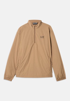 Smėlio spalvos ketvirčio užtrauktuko striukė, pagaminta iš lengvos medžiagos. Savybės: aukštas apykaklės, elastiniai rankogaliai ir mažas logo kairiajame krūtinės pusėje.