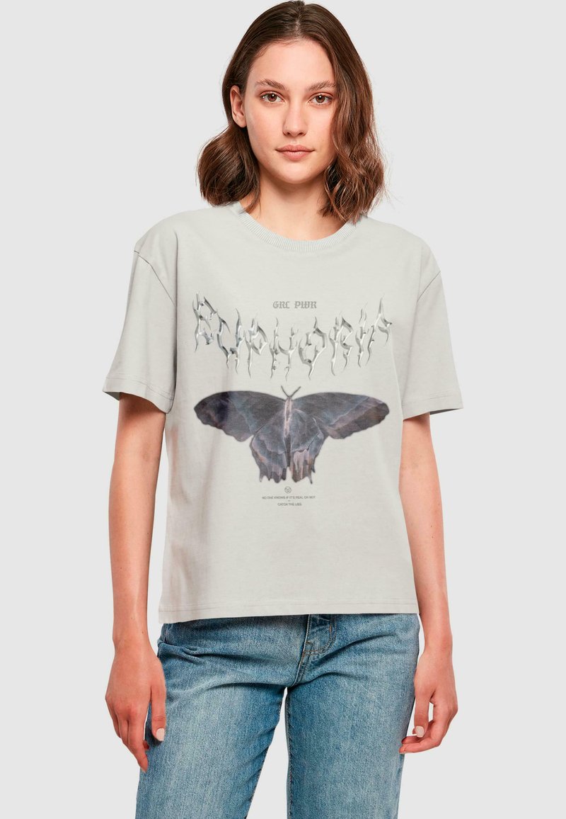 Lys grå bomulds t-shirt med et stort sort sommerfugle grafik og stiliseret tekst. Korte ærmer og en afslappet pasform.