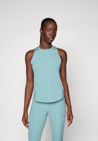 Lichtblauw sporttopje met een ronde halslijn, dunne bandjes en subtiele stiksel details. Gepaard met bijpassende lichtblauwe leggings.