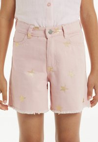 Růžové džíny šortky se zlatým hvězdným vzorem, třepeným lemem, pěti kapsami a zapínáním na knoflík. Vhodné pro běžné nošení.