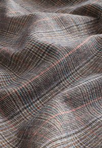 Tessuto intrecciato con motivo a quadri in grigio, marrone e un sottile blu, caratterizzato da una texture morbida e una leggera lucentezza.