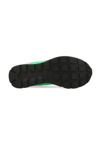 Suola di scarpa sportiva con superficie in gomma nera, caratterizzata da un motivo testurizzato e dettagli verdi sui lati, che garantisce trazione.