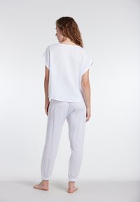 Valkoisesta puuvillasta valmistettu loungewear-setti, johon kuuluu lyhythihainen paita ja joustavilla hihansuilla varustetut housut. Setissä on näkyvissä teksturoitu, kevytrakenne.