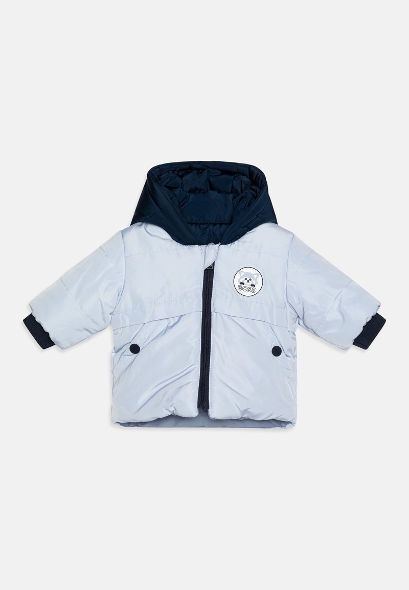 Casaco puffer azul claro com capuz azul marinho, fecho de correr à frente, dois bolsos com botão e um logótipo circular no peito. Mangas curtas.