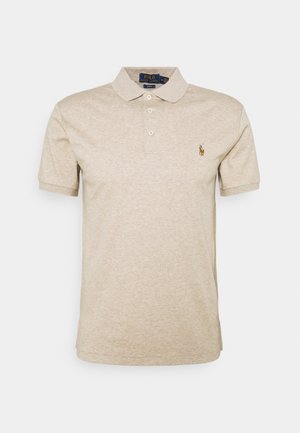 Polo beige à manches courtes avec col, trois boutons, et petit logo brodé d'un joueur de polo sur la poitrine gauche.