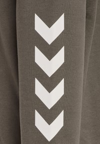 Olivgrüner Sweatshirtstoff mit weißen Chevron-Mustern an den Ärmeln. Das Material wirkt weich und hat eine glatte, gleichmäßige Textur.