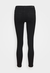 Jeans skinny pretos com uma textura suave, cintura média e dois bolsos traseiros. Apresenta um ligeiro estiramento para conforto e um acabamento limpo.