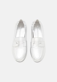 Sølvfarvede metallic slip-on sko med rundet tå, der har en struktureret sløjfe og samlet elastisk kant ved åbningen. Glat finish.