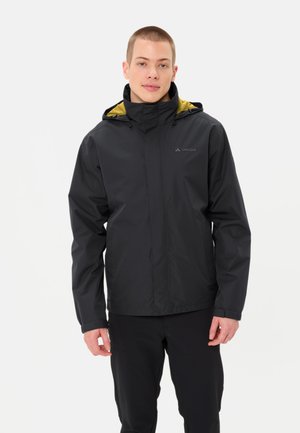 Schwarze wasserdichte Jacke mit einer gelb gefütterten Kapuze, Frontreißverschluss und verstellbaren Bündchen, getragen über schwarzen Hosen. Vaude-Logo auf der Brust.