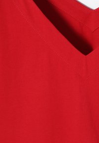 Rød bomuld t-shirt med V-hals-design og synlige syninger. Stoffet ser blødt ud med en glat struktur.