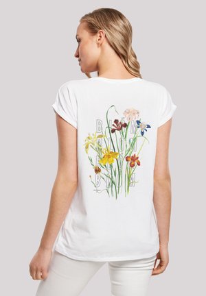 White t-shirt featuring a floral print on the back with various colored flowers and the word "BLOOM" incorporated into the design. Short sleeves.