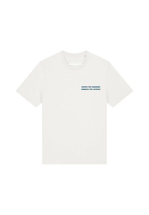 T-shirt blanc uni à col rond et manches courtes avec un petit texte bleu foncé sur la poitrine gauche mentionnant « escape the ordinary embrace the journey ».