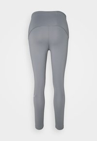 Leggings grigi con una texture liscia, vita alta e design aderente. Presentano dettagli di cucitura sottili e lunghezza fino a metà polpaccio.
