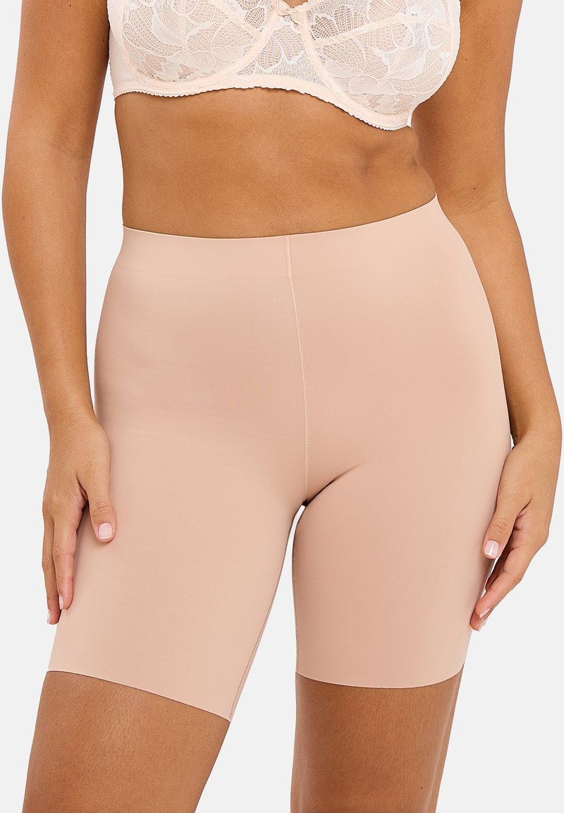 Shorts de vélo rose clair fabriqués dans un matériau extensible et lisse, avec une taille haute et un design sans couture pour un confort optimal et un ajustement épuré.