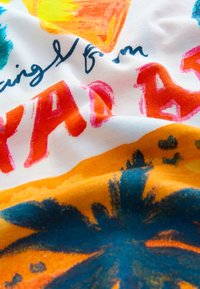 Katoenen stof met levendige kleuren zoals geel, oranje en teal. Het ontwerp bevat abstracte vormen en cursieve tekst in blauw.