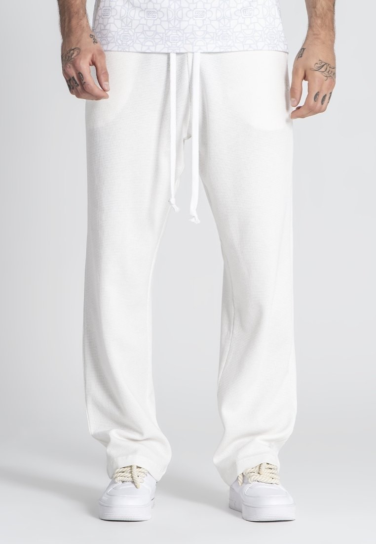 Pantalones de chándal blancos de corte holgado con tejido texturizado, cintura elástica con cordón y bolsillos laterales.