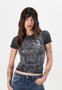 Melns grafiskais T-krekls ar īsām piedurknēm, ar nolietotu drukas dizainu pelēkā un baltā krāsā, kontrastējošām šuvēm ap kakla izgriezumu.