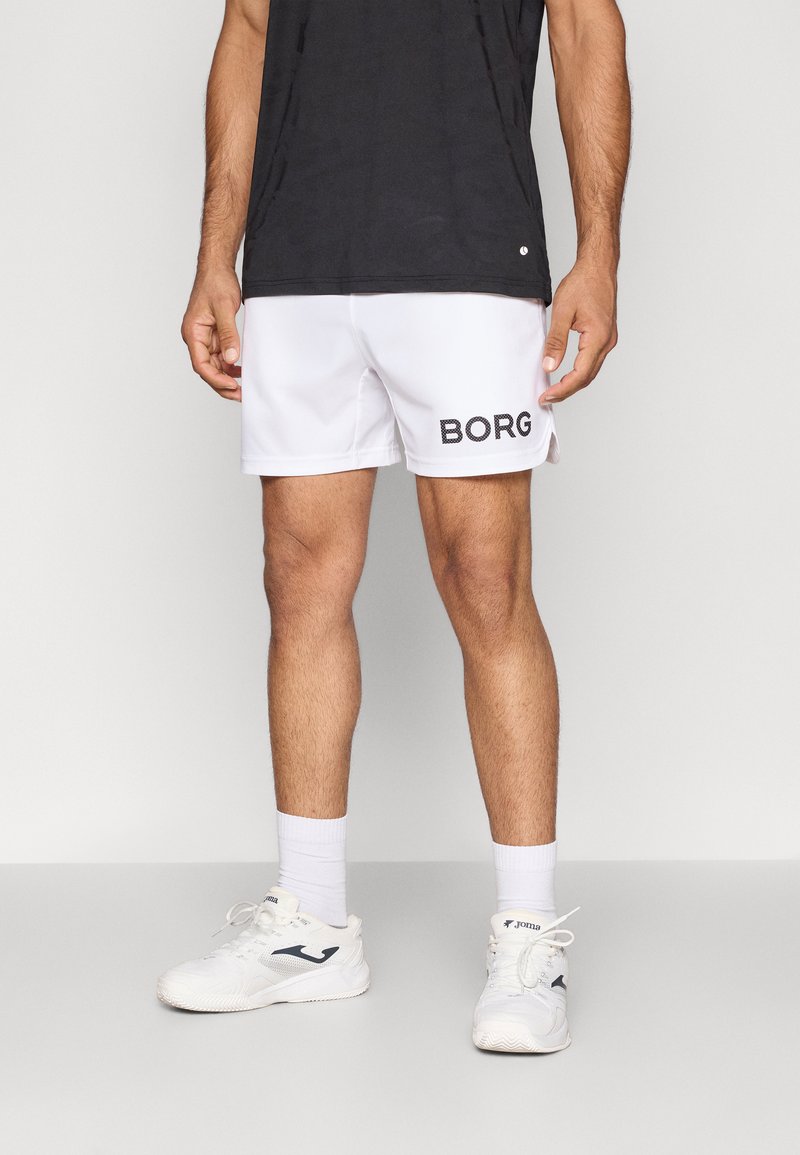 Bermudas brancas de desporto com o logo preto "BORG", tecido leve, cintura elástica. Usadas com ténis brancos e meias de cano curto.