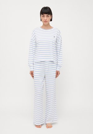 Långärmad, vit pyjamaströja med blå ränder, ihop med matchande vida byxor, tillverkad av mjukt tyg, med en liten logotyp på bröstet.