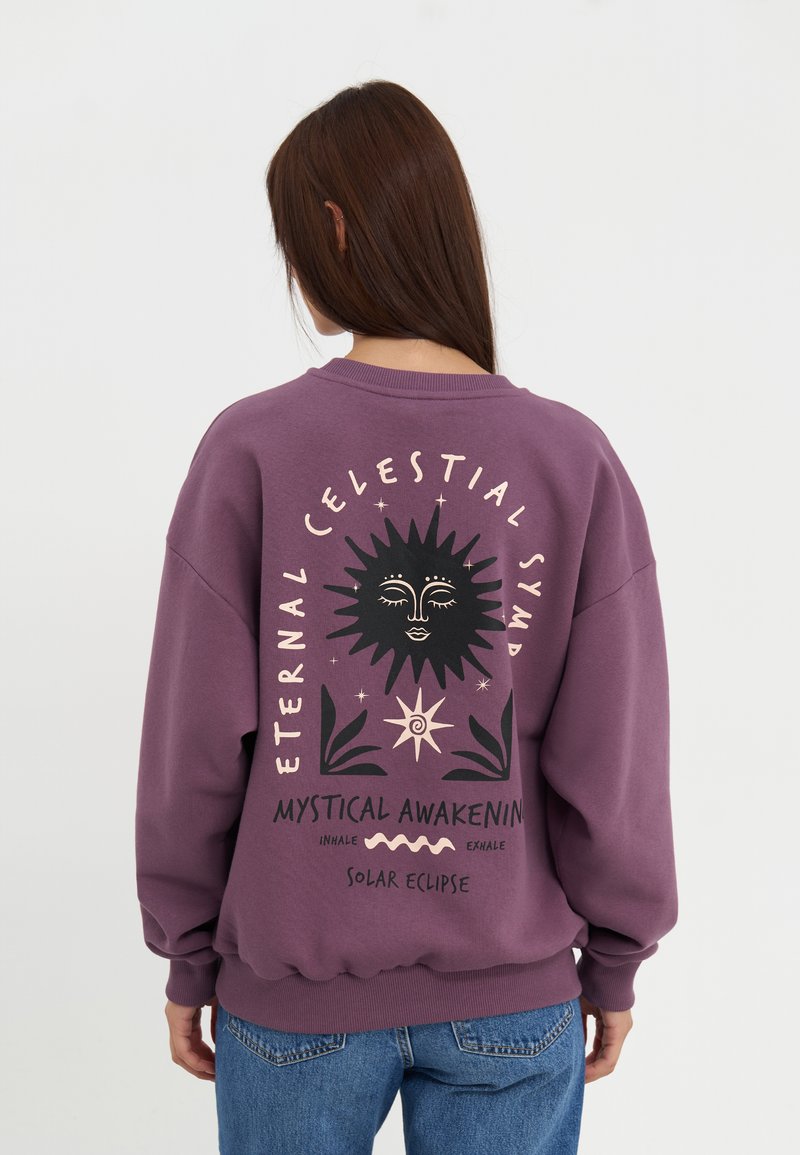 Paarse sweatshirt met een grafische print van een zon en tekst op de achterkant. Heeft een ronde hals, lange mouwen en geribde manchetten.