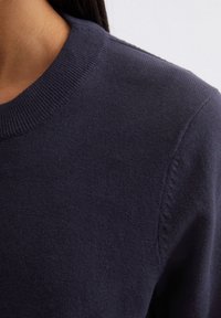 Marineblauwe gebreide trui met een ronde halslijn en geribbelde manchetten, met een zachte, gestructureerde stof en een nette, gladde afwerking.