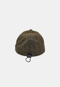Casquette en tissu chevrons marron avec un dessus arrondi, un détail en boucle à l'arrière et deux œillets de ventilation. Fermeture réglable à l'arrière.