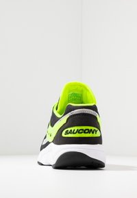 Sneaker Saucony nera e verde neon con una tomaia in rete e camoscio, collo imbottito e una suola intermedia bianca con branding sul tallone.