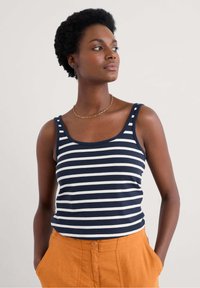 Mörkblå och vit randig ärmklippt linne med rundad halsringning, i kombination med orange linneshorts med hög midja.