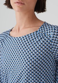 Blau gemusterte Bluse mit geometrischem Design und Kästchen in Blau- und Cremetönen, aus weichem Stoff und in lockerer Passform.