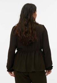 Donkerbruine blouse met een geplooide taille, lange mouwen en geruchte manchetten. Gestructureerde stof met een zacht, vloeiend ontwerp.