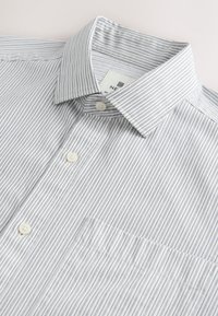 Camicia a righe con bottoni, caratterizzata da un motivo azzurro e bianco, colletto a risvolto, tasca anteriore e chiusura con bottoni su un tessuto liscio.
