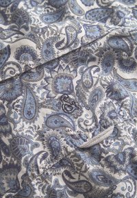 Tessuto stampato con motivi paisley in blu e grigio, con una texture morbida e una leggera lucentezza, che mette in mostra dettagli floreali intricati.